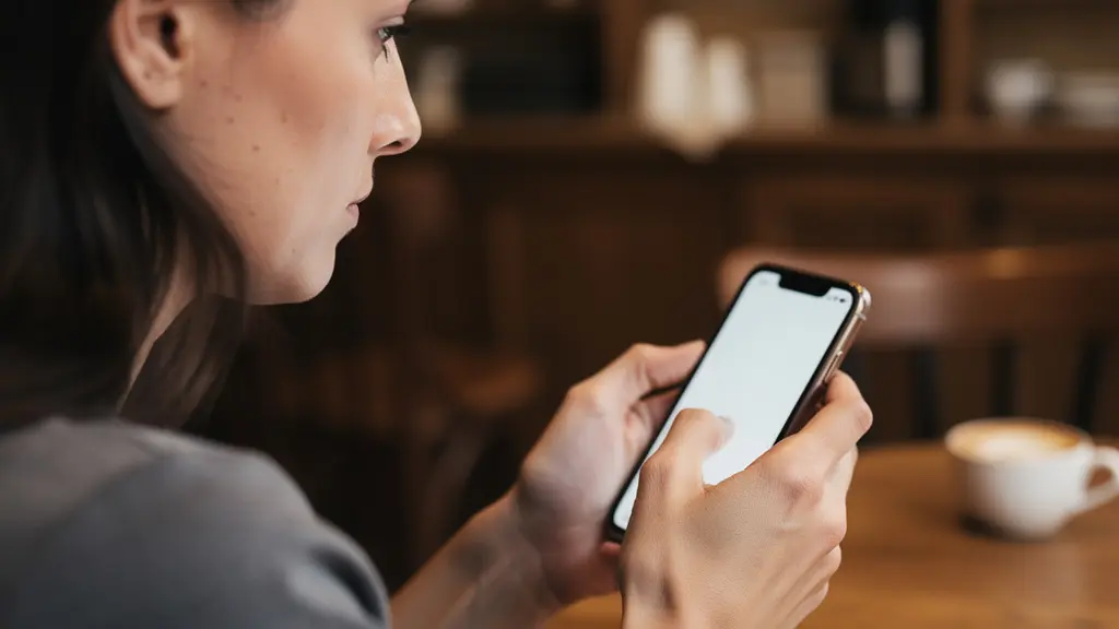 Femme consultant son smartphone pour une simulation de prêt immobilier dans un café