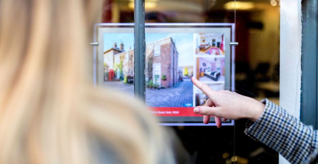 Photographe immobilier professionnel prenant des photos d'un salon home stagé avec équipement visible